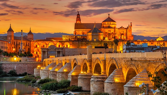 Vista nocturna en la Mezquita-Catedral con puente romano en Córdoba