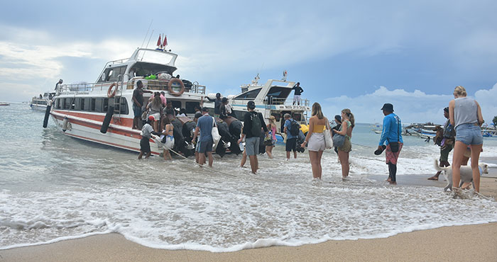 Tourists queue up to board a speedboat at Sanur Beach