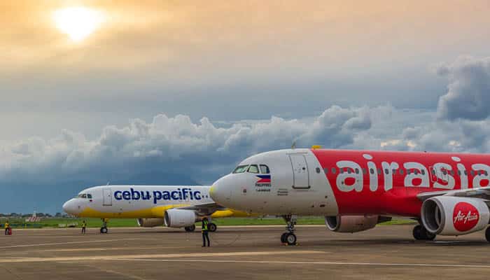 Low cost airlines Cebu Pacific and Air Asia aircraft at colorful sunset at Puerta Princesa Airport in Palawan island