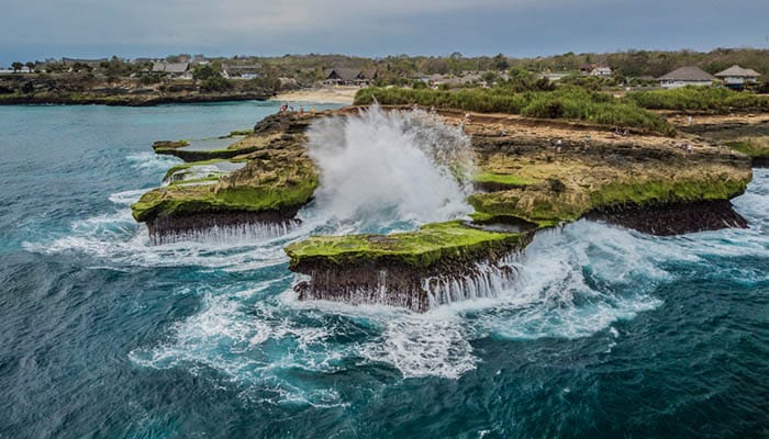 Giant wave breaking on Nusa Lembongan cliffs in Bali view from a drone