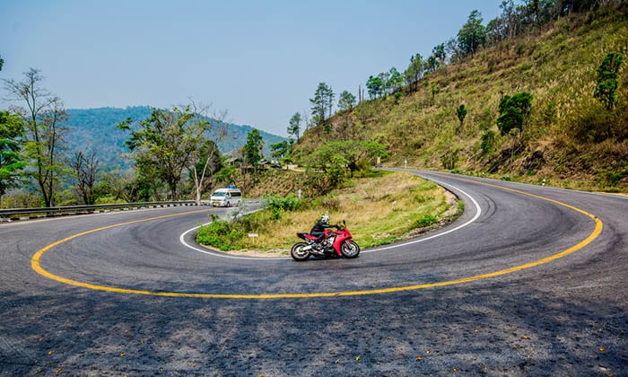 A motorcycle and a minivan on a curvey road in Pai, Mae Hong Son Thailand.