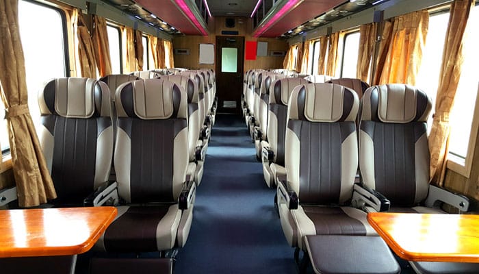 Picture of the long-distance seating cabin of a Vietnam Train. With tables and empty seats.